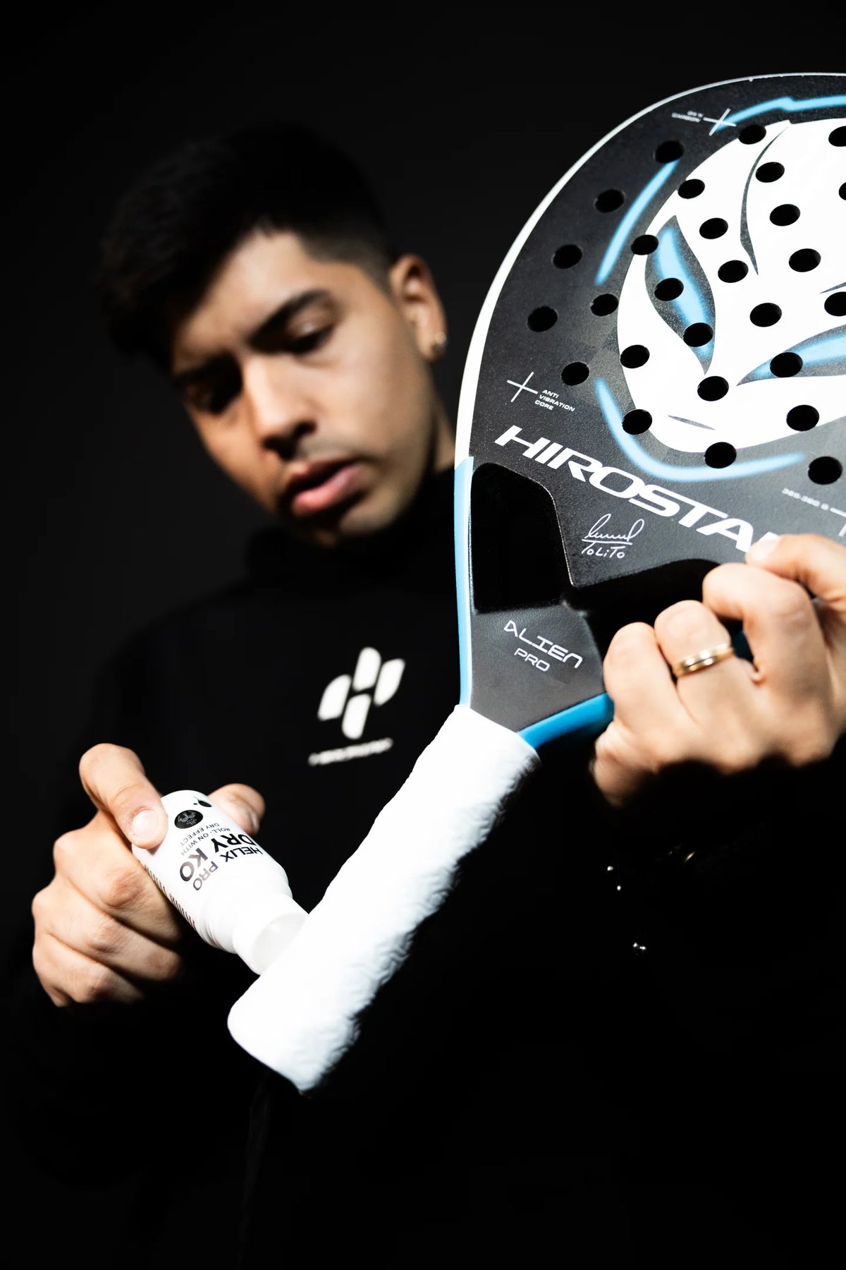 Padelspieler trägt den Helix Pro DRY KO Roll-On direkt auf den Schlägergriff auf